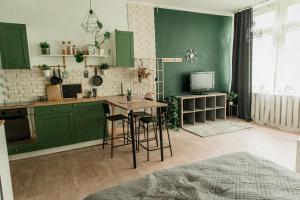 a kitchen with green cabinets and a table with stools at Studio type apartment in Ķegums in Ķegums