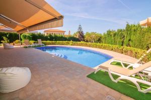 una piscina con 2 tumbonas y una sombrilla en Bellviure Luxury Villa, en Marratxí 