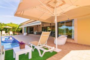 eine Terrasse mit 2 Stühlen und einem Sonnenschirm neben einem Pool in der Unterkunft Bellviure Luxury Villa in Marratxí 