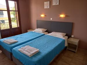 Dos camas en una habitación con sábanas azules. en KOSTAS APARTMENTS, en Sidari