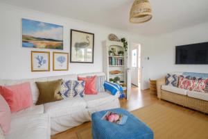 a living room with a white couch with colorful pillows at 54 Linden Road in Aldeburgh