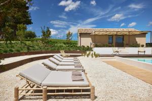a row of chaise lounges next to a pool at Casale Tre Gelsi in Cingoli
