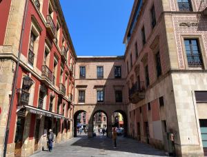 an alley between two buildings with people walking through it at MyHouseSpain - Acogedor apartamento plaza mayor Gijón 1 in Gijón