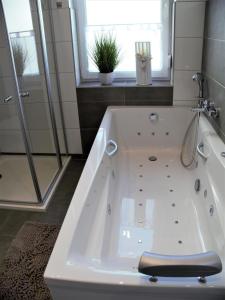 a white bath tub in a bathroom with a window at FeWo Sonnenschein mit Whirlpoolbadewanne in Bad Harzburg