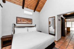 a bedroom with a white bed and a mirror at Kruger Gate Hotel in Skukuza