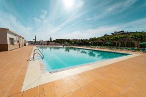 a large swimming pool with blue water in a courtyard at Kampaoh Costa del Sol in Caserío Almayate Bajo