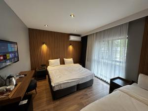 ein Hotelzimmer mit 2 Betten, einem Schreibtisch und einem TV in der Unterkunft Bademi Room in Edirne