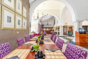 a dining room with long tables and purple chairs at Mercure Johannesburg Randburg in Johannesburg