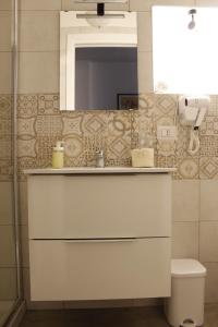 een badkamer met een wastafel, een spiegel en een toilet bij La pergola home in Barletta