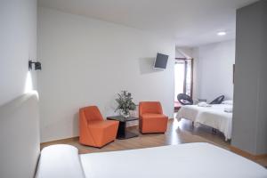 ein Schlafzimmer mit zwei orangenen Stühlen und einem Bett in der Unterkunft Hotel Montañés in Suances