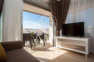 a living room with a television and a table with chairs at Casa Munteanu Ivan Luxury Homes 6ªPlta Norte 1ªLinea in Oropesa del Mar