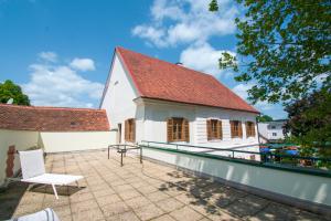 a white building with a red roof and a patio at Das Torhaus in Feldbach