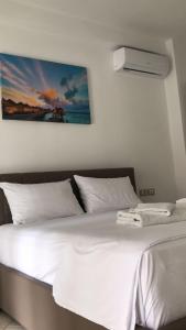 a bedroom with a white bed with a picture on the wall at Lion's Apartments Vlora in Vlorë +11 photos