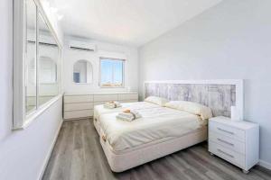 una camera bianca con un grande letto e una finestra di BENALBEACH APARTAMENTO con vistas maravillosas a Málaga