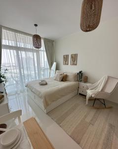 a white bedroom with a large bed and a chair at Tranquil Studio in Damac Hills in Dubai