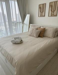 a white bed with two towels on top of it at Tranquil Studio in Damac Hills in Dubai