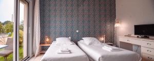 a hotel room with two beds and a tv at Hôtel Restaurant La Voile Bleue in Erdeven