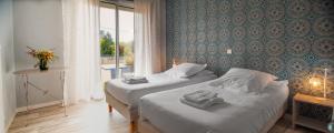 a hotel room with two beds and a window at Hôtel Restaurant La Voile Bleue in Erdeven
