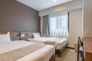a hotel room with two beds and a window at Hotel Sanrriott Osaka Hommachi in Osaka