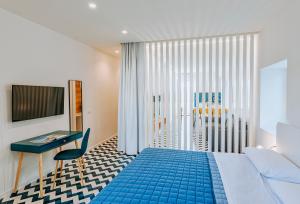 sypialnia z niebieskim łóżkiem, biurkiem i oknem w obiekcie Davalos 14 Luxury Home w mieście Ischia