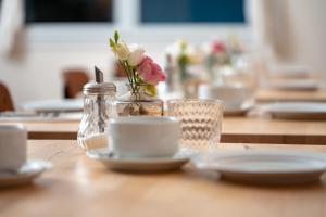 a table with plates and a vase with flowers in it at Hôtel Restaurant La Voile Bleue in Erdeven