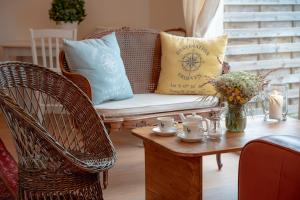 a living room with a wicker couch and a coffee table at Hôtel Restaurant La Voile Bleue in Erdeven