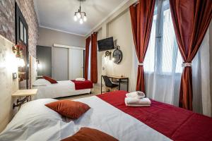 una camera d'albergo con due letti con tende rosse di HOTEL VENETO con accesso ZTL a Firenze