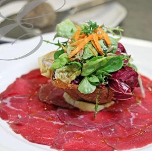 einen Teller mit Salat auf einem Sandwich mit roter Soße in der Unterkunft Hotel & Restaurant Eggers GmbH in Sprockhövel