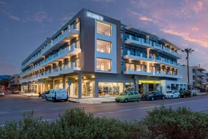 a large building with cars parked in a parking lot at Kos Divine Hotel & Suites in Kos