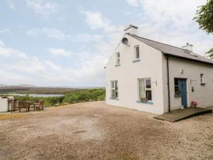 a white cottage with a gravel driveway at Lough View Cottage in Carrigart
