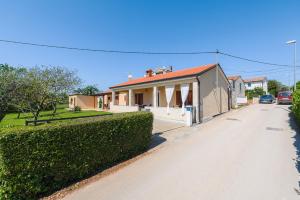 a house with a hedge in front of a street at MIMA house with apartments in Savudrija
