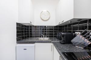 een keuken met een wastafel en een klok aan de muur bij King's Cross Apartments in Londen