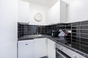 a kitchen with white cabinets and a clock on the wall at King's Cross Apartments in London