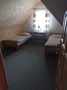 a attic room with two beds and a table at U Wyrostków in Gliczarów Górny
