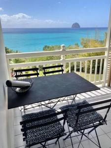 un tavolo nero e sedie su un balcone con vista sull'oceano di Studio vue mer et rocher du Diamant Antilles a Le Diamant