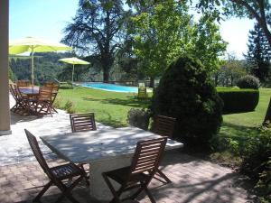 un patio con tavolo, sedie e piscina di Coumassous a Arricau-Bordes