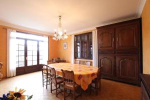 una sala da pranzo con tavolo, sedie e lampadario pendente di Coumassous a Arricau-Bordes