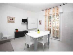 a kitchen with a white table and white chairs at Pinetina Beach in Bibione