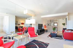a living room with red chairs and a couch at StayCentral - Spacious Seaviews Port Melbourne in Melbourne