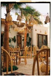 a patio with palm trees and a table and chairs at Blue Waves Surf House - Anza I in Agadir