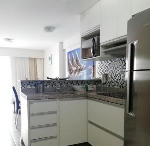 a kitchen with white cabinets and a stainless steel refrigerator at Beach Class Rosalux 707 in Fortaleza