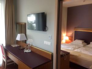 塞克什白堡的住宿－森特蓋勒特酒店，一间卧室配有一张床和一张桌子,墙上配有电视