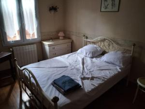 a bed with white sheets and a blue bag on it at Chez Coco maison au coeur du parc régional du Quercy in Issendolus