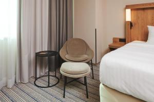 a hotel room with a bed and a chair next to a bed at Courtyard by Marriott Warsaw Airport in Warsaw
