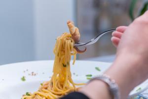 a person eating a plate of pasta with shrimp on a fork at Hotel America in Marina di Camerota