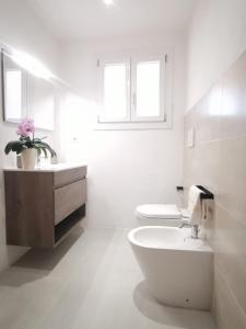 a white bathroom with a toilet and a sink at Appartamento due passi dal mare in Fort Village