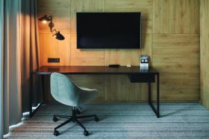 a desk with a chair and a television on a wall at Courtyard by Marriott Warsaw Airport in Warsaw
