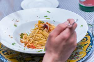 a person eating a plate of pasta with shrimp at Hotel America in Marina di Camerota