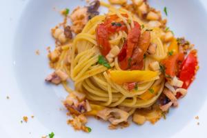 a plate of pasta with bacon and other vegetables at Hotel America in Marina di Camerota