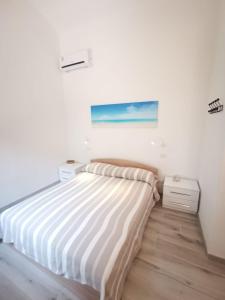 a white bedroom with a bed and a painting on the wall at Appartamento due passi dal mare in Fort Village
